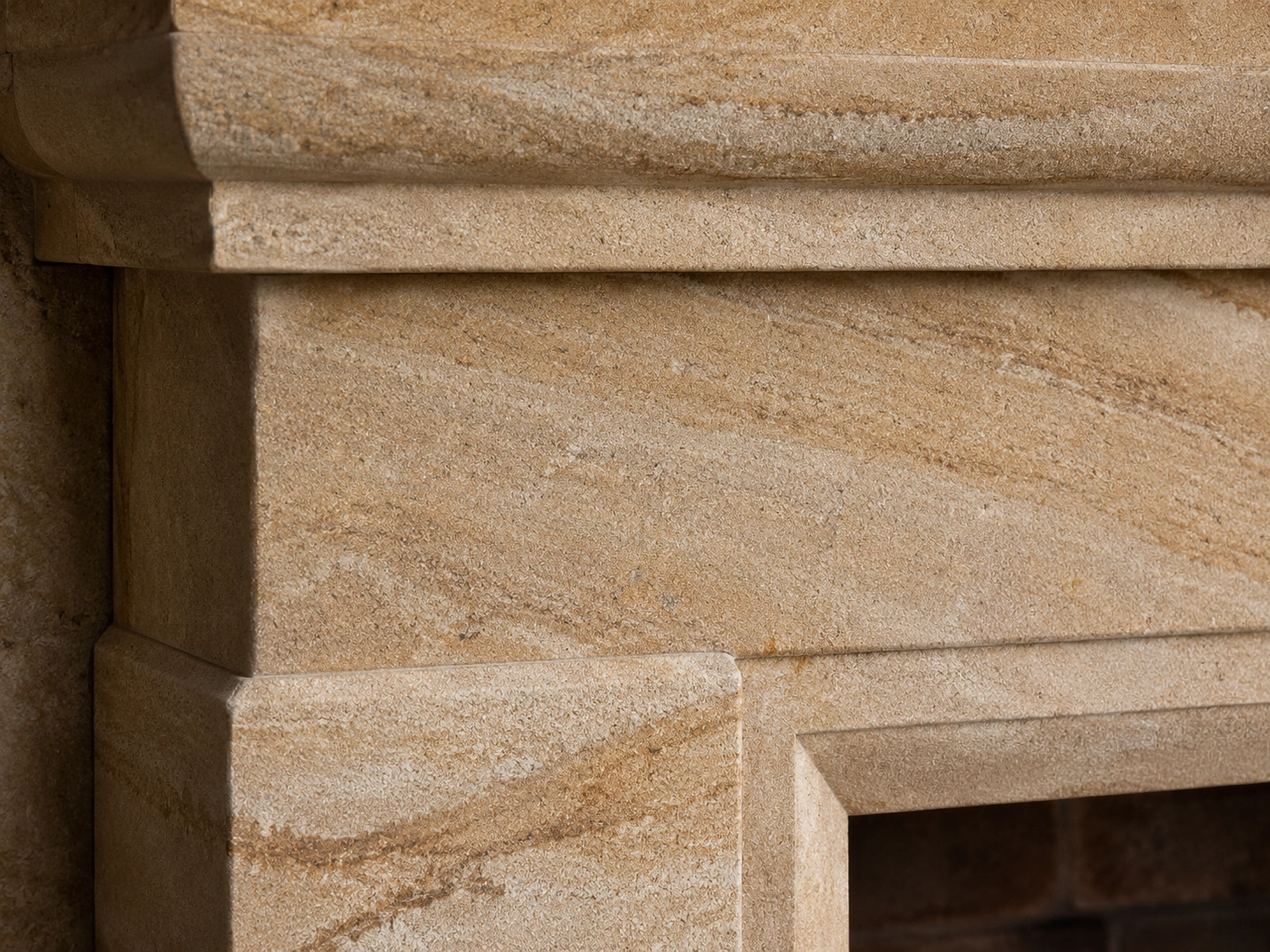 Close-up view of natural sandstone fireplace surround showing unique texture and warm tones